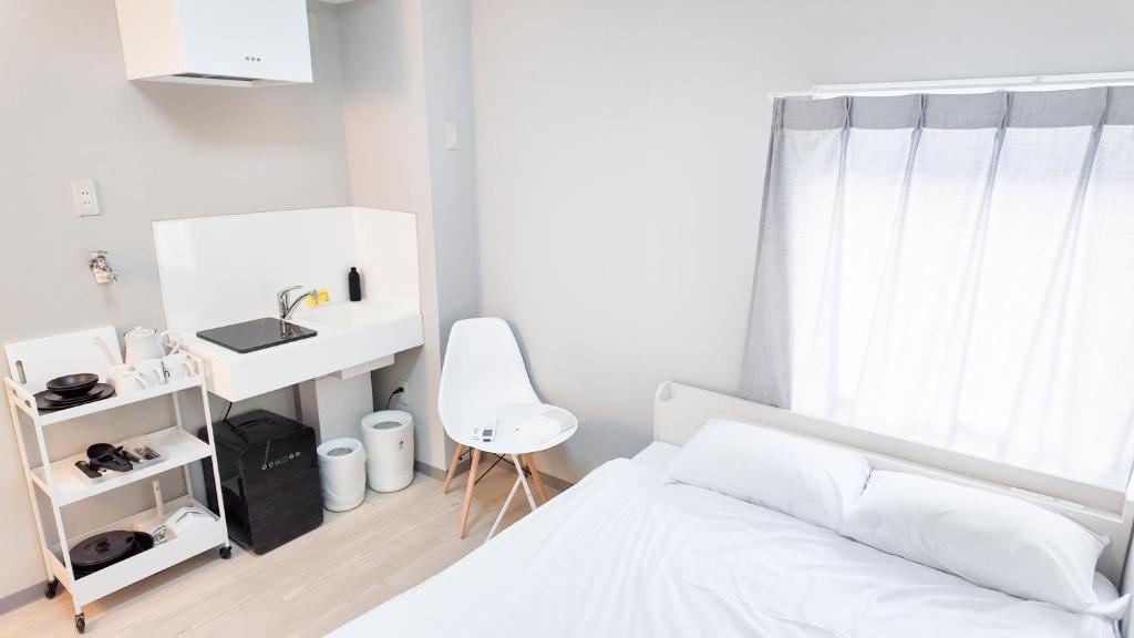 Un dormitorio blanco con una cama y un escritorio. en 9stay蔵前, en Tokio