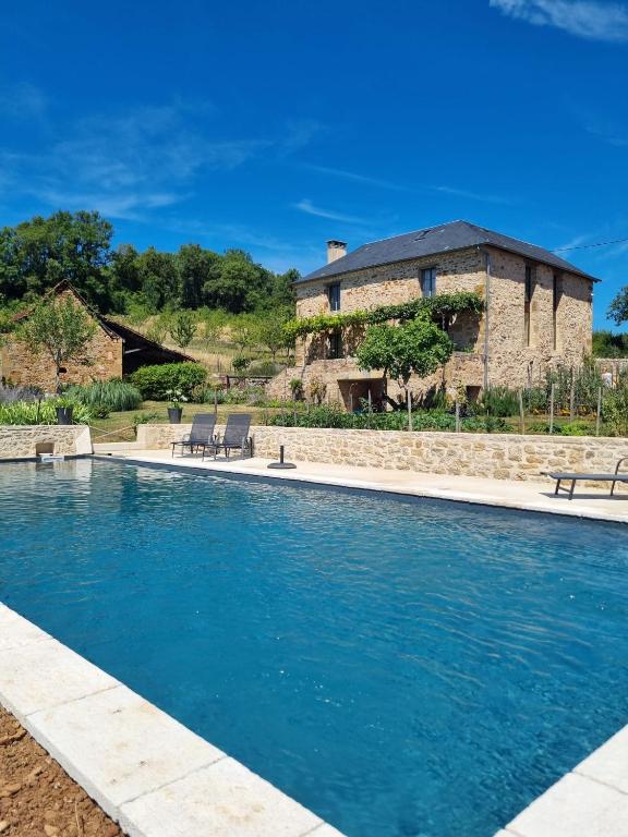 a swimming pool with a house in the background at Les Peyronnies in Figeac