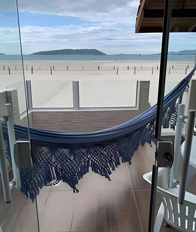 a hammock on the beach looking out at the beach at Ocean Residence - Aptos Pé na Areia Ponta do Papagaio in Palhoça