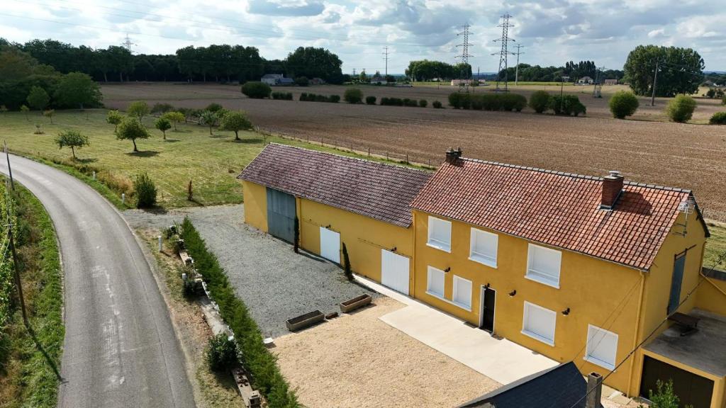 une maison jaune à côté d'un champ et d'une route dans l'établissement Le Flocon- Campagne - 6 pers - Rêve au Mans, à Laigné-en-Belin