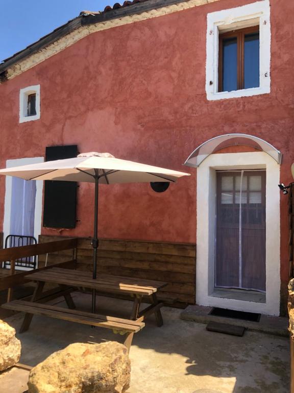 a picnic table with an umbrella outside of a house at House 2 people in Castaignos-Souslens