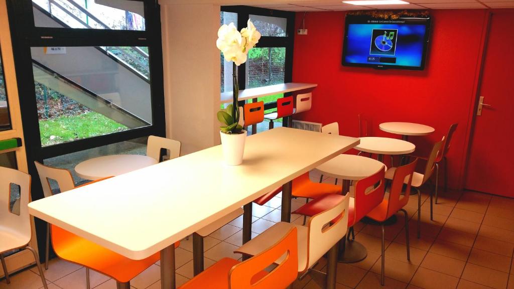 a dining room with tables and chairs and a tv at Premiere Classe Quimper in Quimper