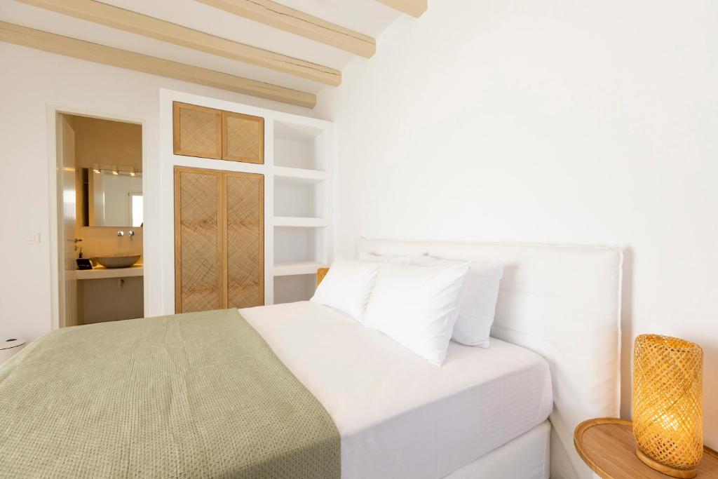 a white bedroom with a bed and a bathroom at Cycladic Suites in Naousa