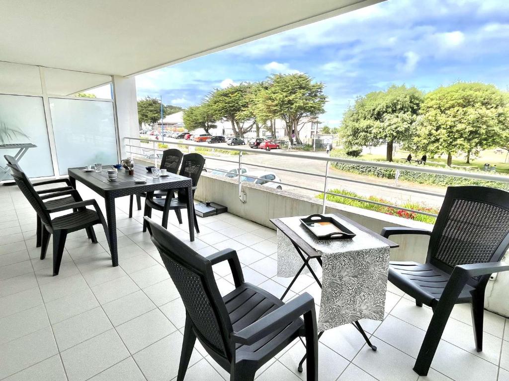 a patio with tables and chairs on a balcony at Étel - Appartement 2 pièces - 42 m² - Vue mer - Wifi - Animaux admis - Parking - FR-1-479-165 in Étel