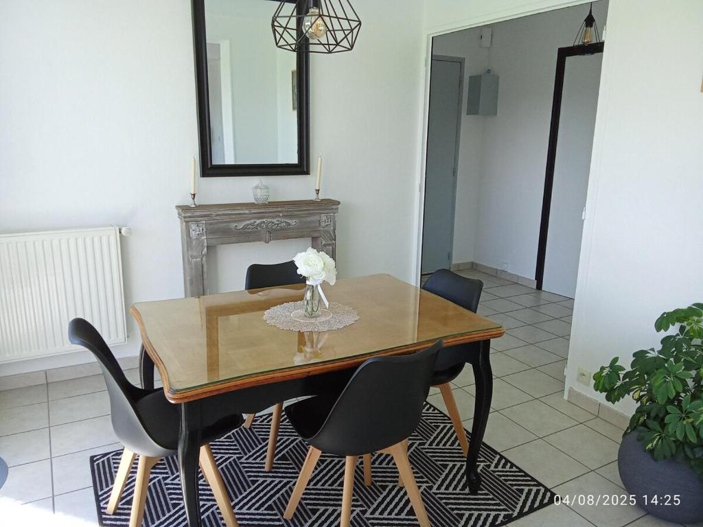 a dining room table with chairs and a vase of flowers at T2 - Terrasse avec vue imprenable - Secteur gare in Poitiers