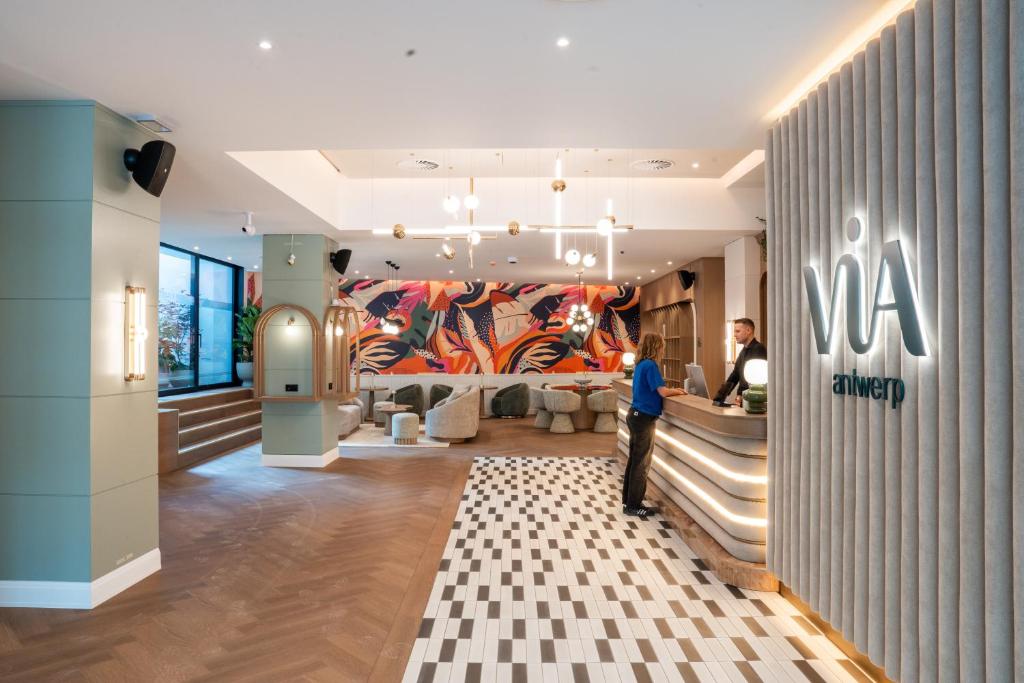a woman standing in a store lobby with a mural at Via Antwerp in Antwerp