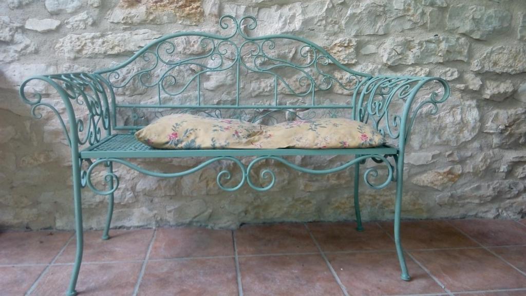 a green bench with pillows sitting against a stone wall at Casa Rural Fuentetrigo in Brizuela