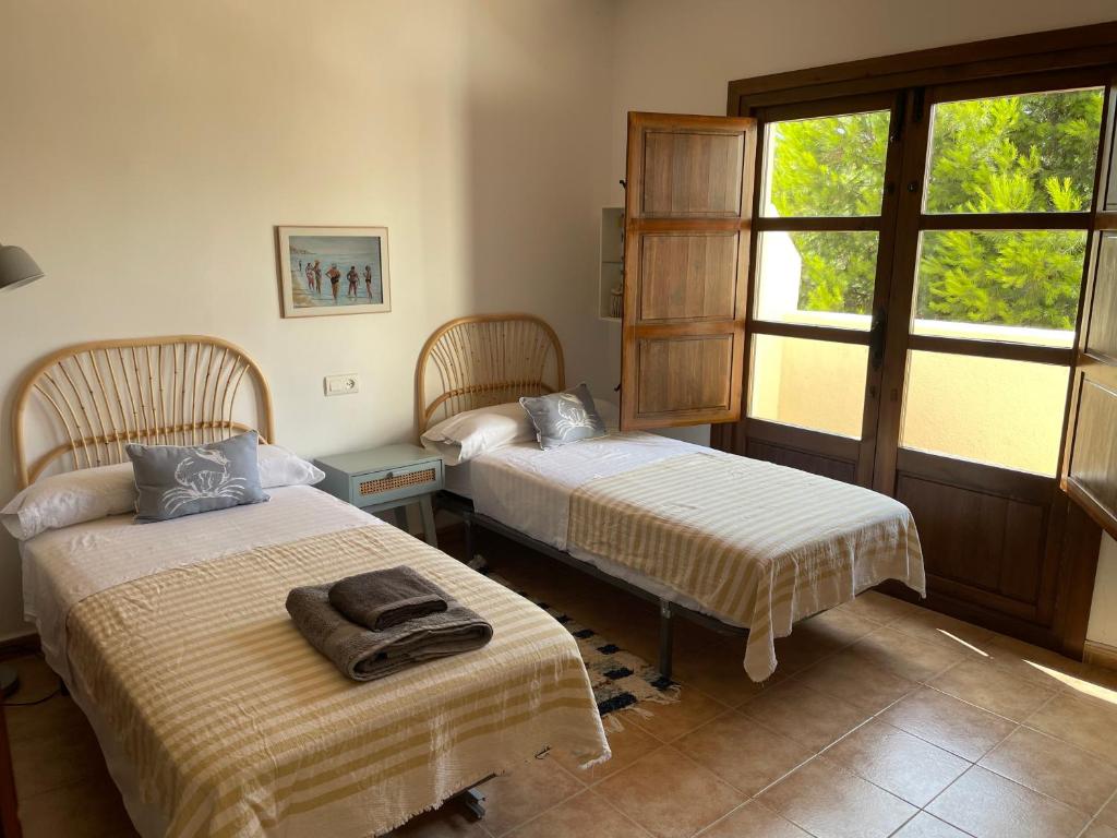 ein Schlafzimmer mit zwei Betten und einem Fenster in der Unterkunft Casa Buganvilla con piscina en San José Sotillo in San José