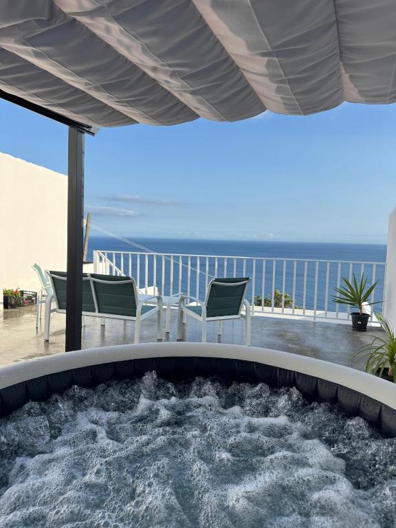 a hot tub on a deck with the ocean in the background at Raízes AL in Povoação