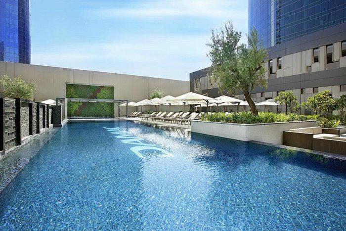 a large swimming pool in a building with umbrellas at Vogue Vacation Homes, Business Bay Damac Cour Jardin close to Downtown, Burj Khalifa and Dubai Mall, Studio Apartment with City View, Access to all Amenities in Dubai