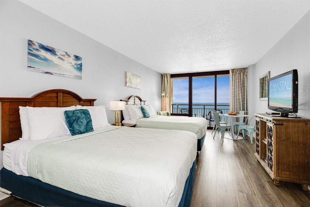 ein Hotelzimmer mit zwei Betten und einem Flachbildfernseher in der Unterkunft WINTER RATES! OceanviewStudio Full Kitchen, Dogs OK! 1128 in Myrtle Beach