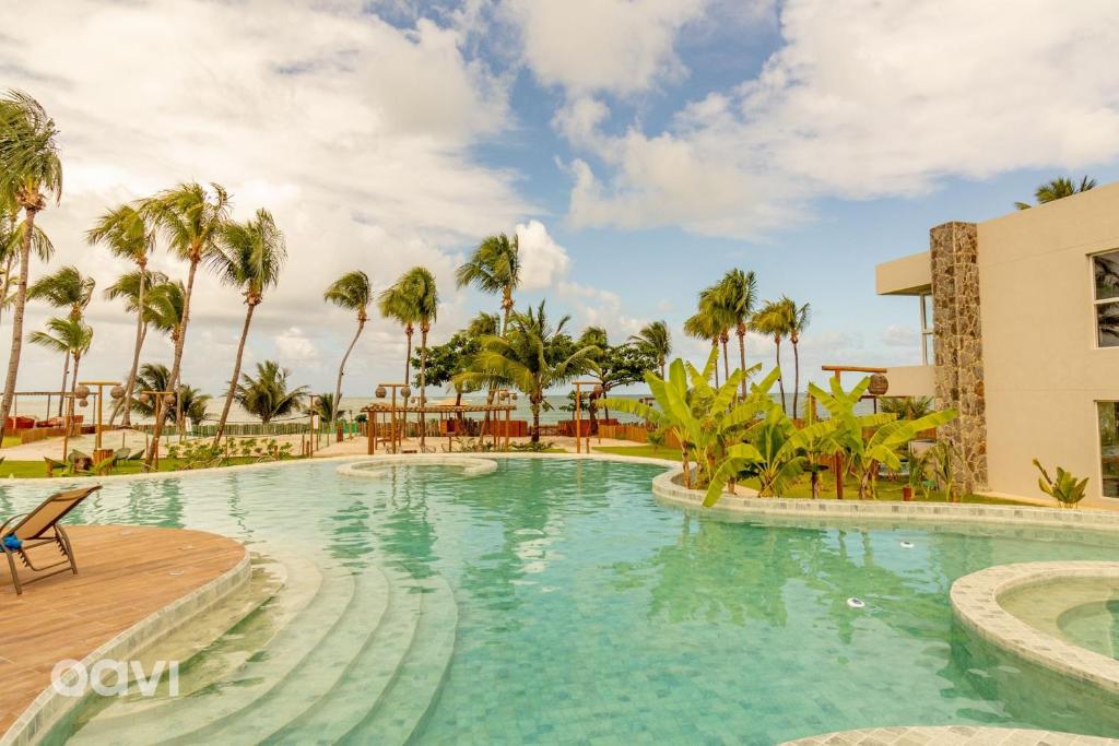 a pool at a resort with palm trees at Milagres - Naluum Residence in Passo de Camarajibe