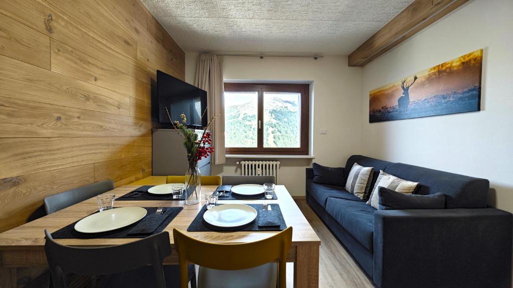 a living room with a table and a blue couch at Hostdomus - Rainbow Apartment in Sestriere