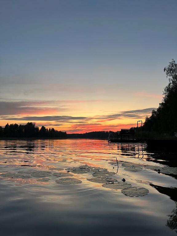 a view of a lake with a sunset in the background at Semi-detached cottage by the lake in Jyväskylä