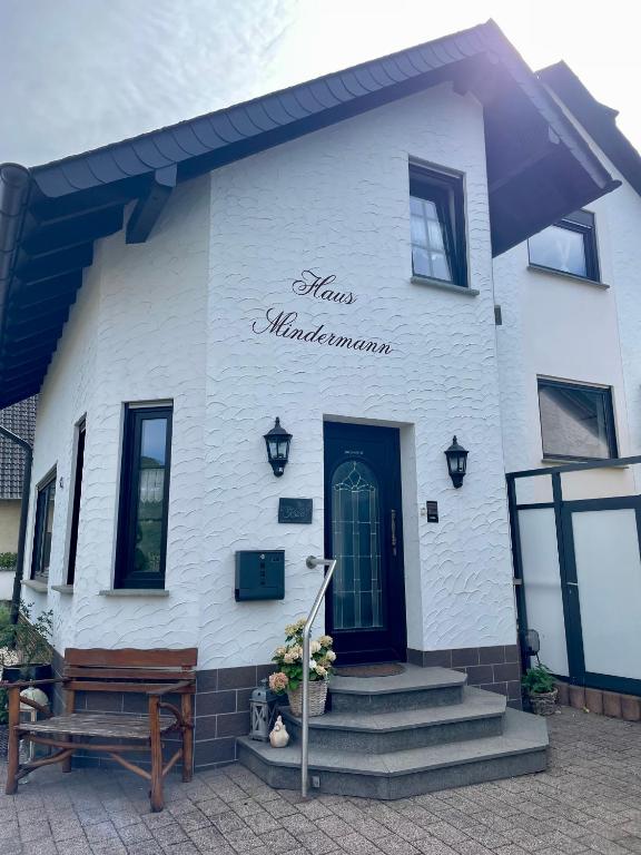 a white building with a blue door and stairs at Haus Mindermann in Bruttig-Fankel