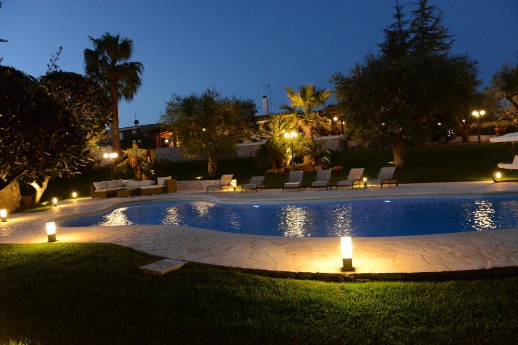 a swimming pool with lights in a yard at night at Una Perla Nel Verde in Putignano