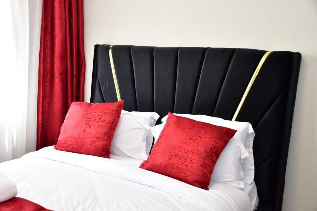 a bed with two red pillows on it at Rieyo Homes Studio near Airport and SGR Train Station in Nairobi