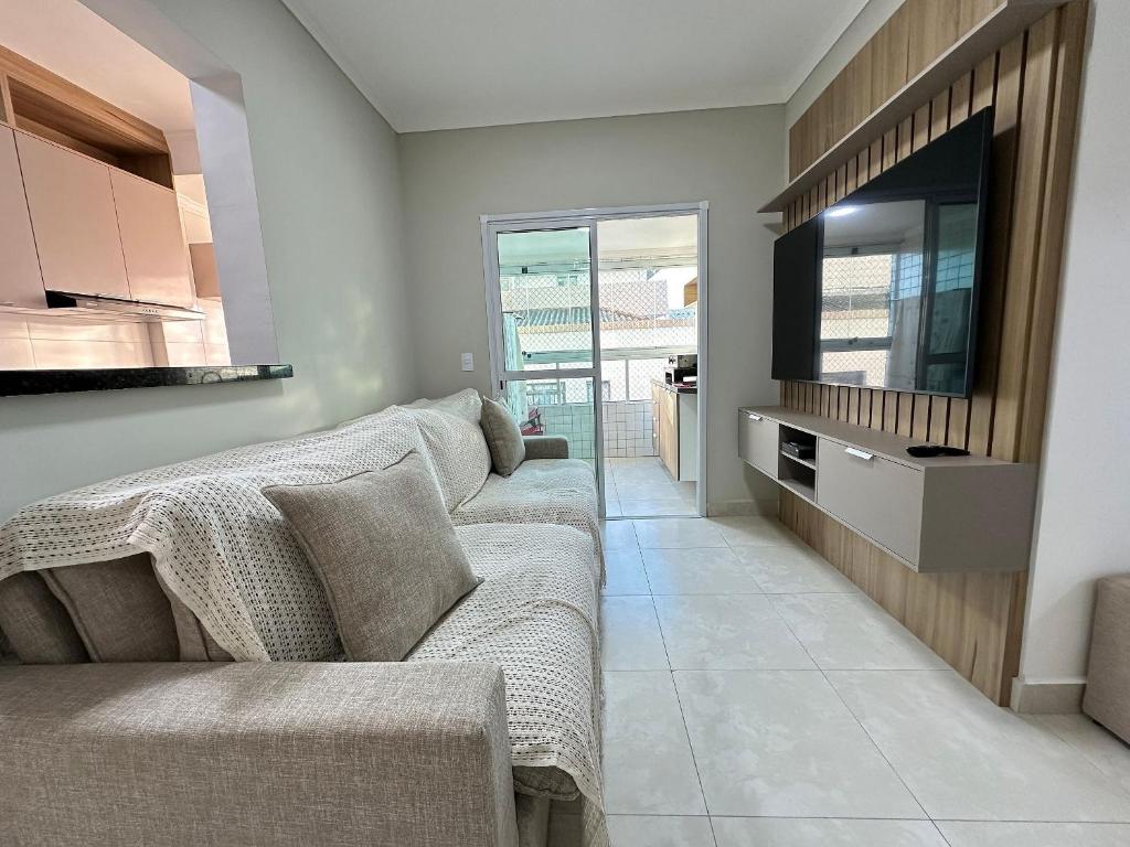 un salon avec un canapé et une télévision à écran plat dans l'établissement Apto Alto Padrão Aviação 2Qts (1Suíte), à Praia Grande