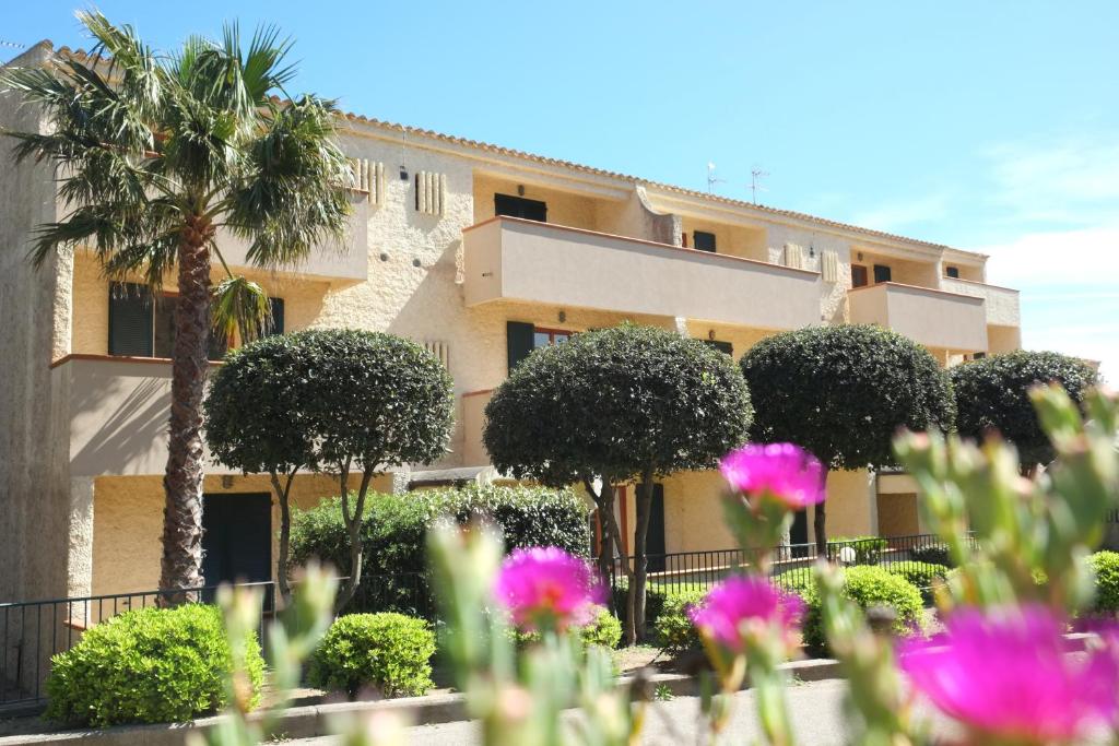 un edificio con una palmera y flores rosas en Blu Baita, en La Maddalena