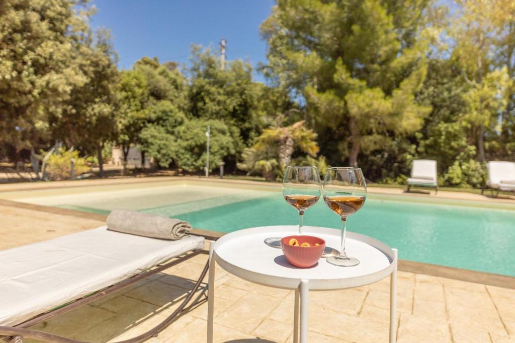 - deux verres de vin assis sur une table à côté d'une piscine dans l'établissement Villa Oasi verde, à Specchiolla