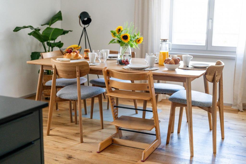a wooden dining room table with chairs and flowers on it at SOLUNA STAY I See & Berge I Luzern I Familienfreundlich I Ski I Self-check-in I Free Parking in Küssnacht