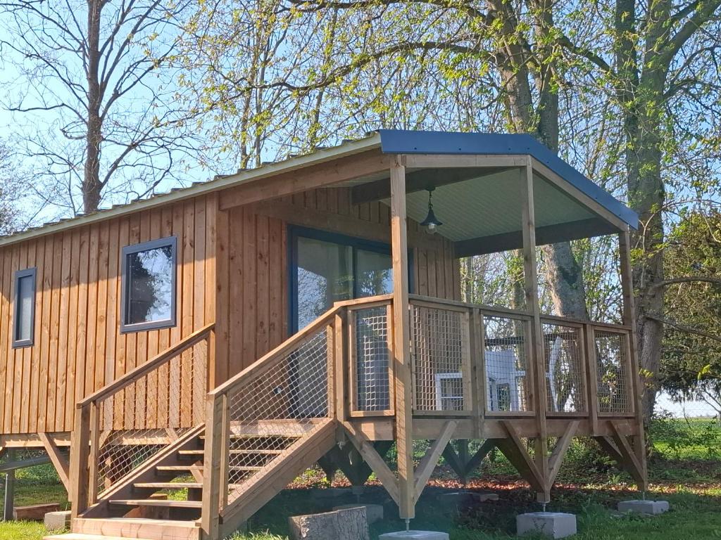 a cabin in the woods with a large deck at Les Cabanes d'Isa - Cab'Vert in Flexanville
