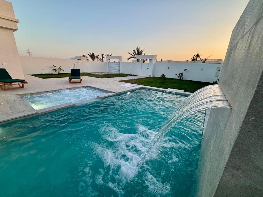 a pool with a water fountain in a building at Magnifique Villa Kayo, Djerba in Arkou