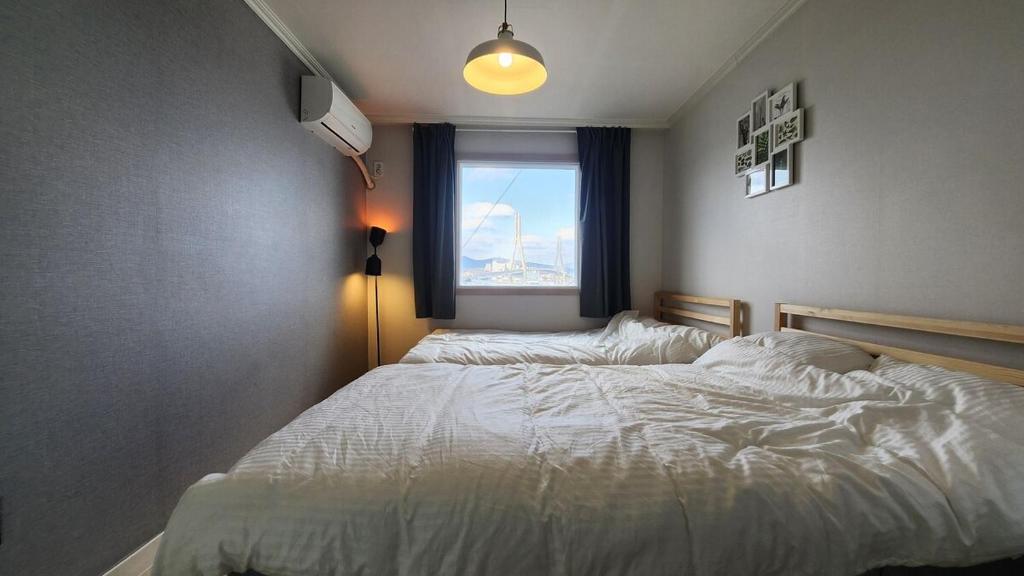 a bedroom with a white bed with a window at Santiago Ocean View House in Busan