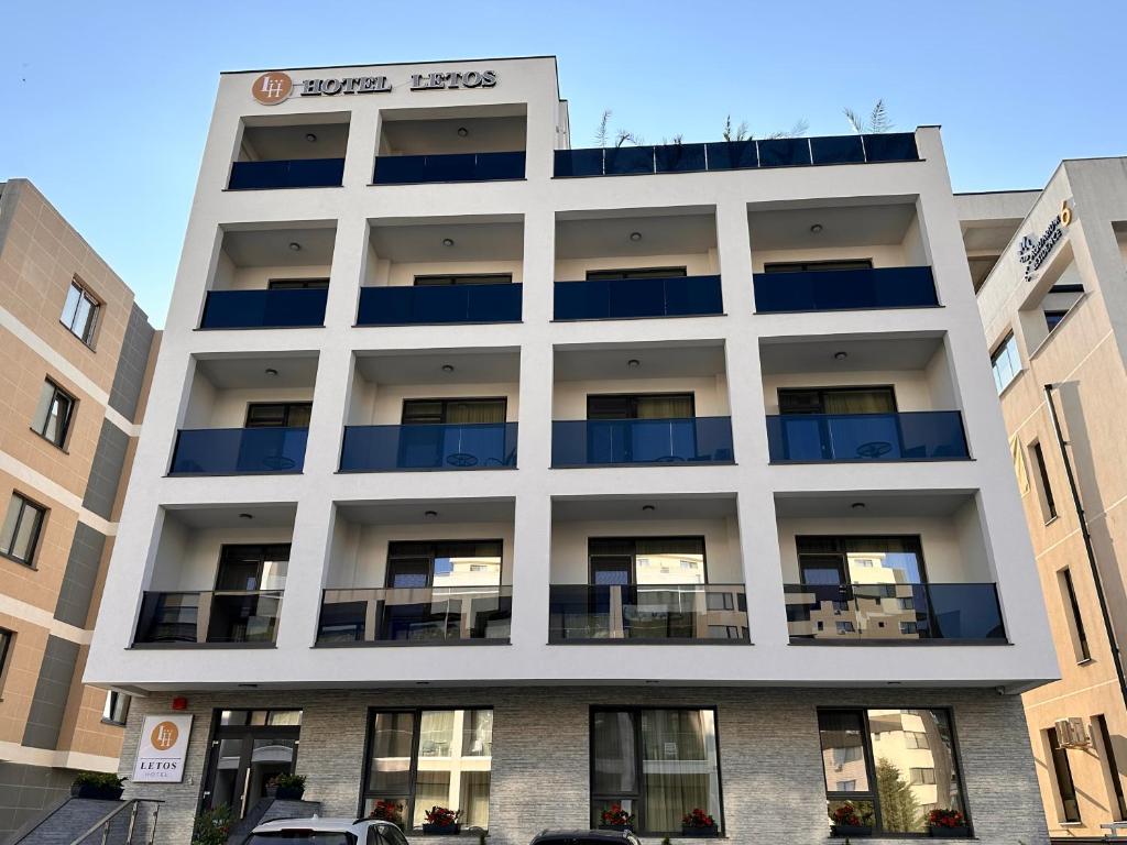 a white building with blue balconies on it at Hotel Letos Mamaia Nord in Mamaia Sat/Năvodari