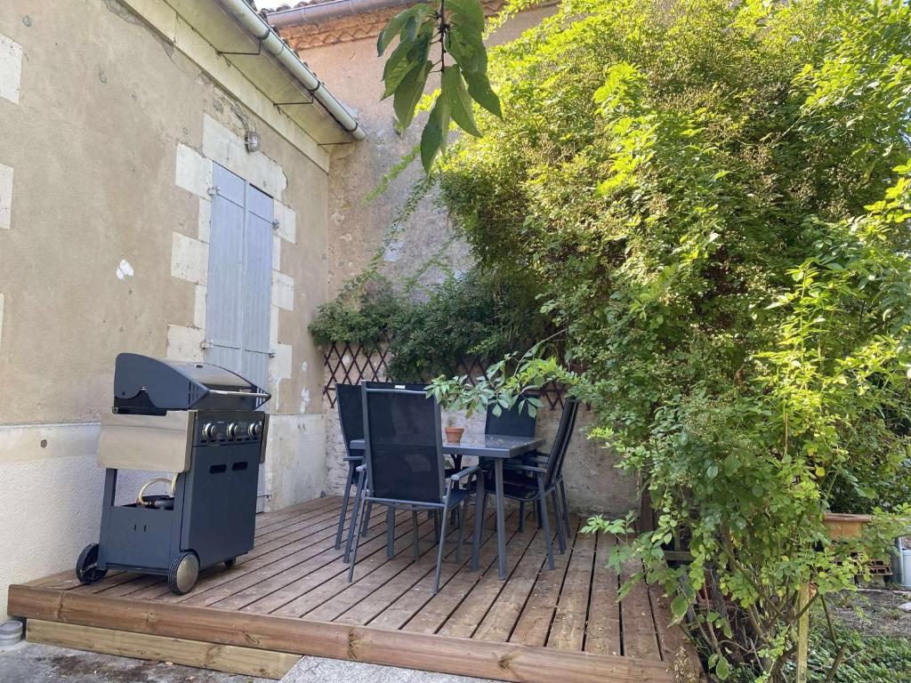 un barbecue e un tavolo con sedie su una terrazza di Bienvenue chez Lou a Saint-Aubin-de-Blaye