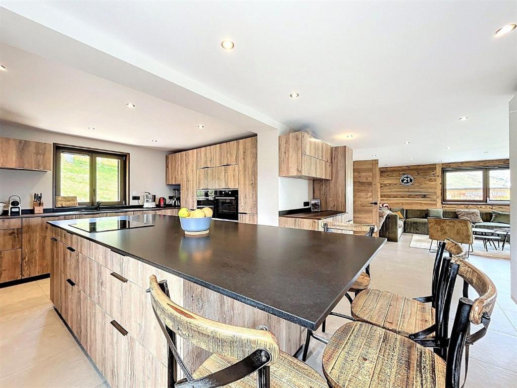 a kitchen with wooden cabinets and a large island with chairs at Chalet Savoyard de Luxe pour 14 personnes avec sauna et animaux admis - FR-1-267-311 in La Toussuire