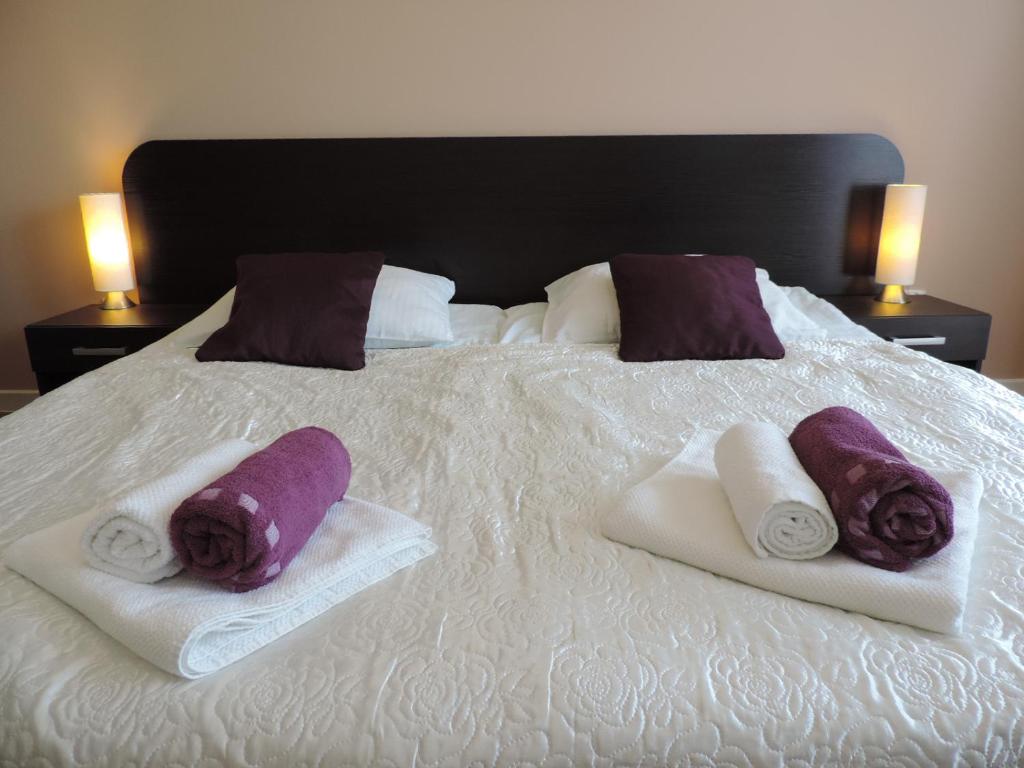 a bed with towels and purple pillows on it at Apartament Green in Krosno