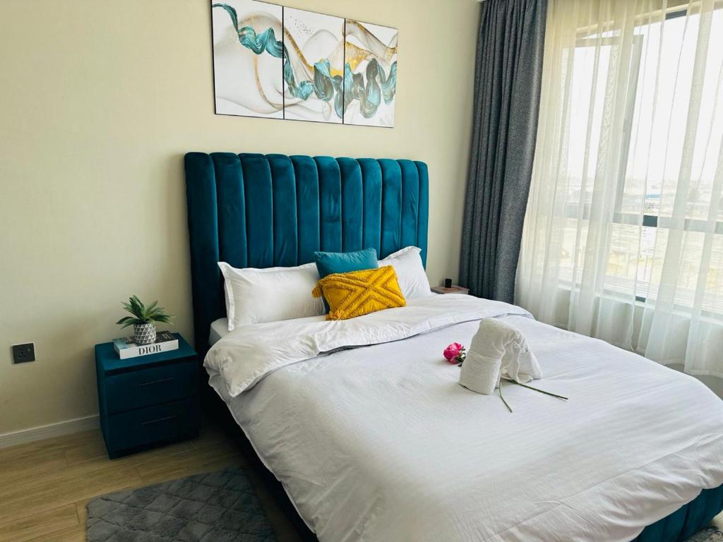 a bedroom with a large bed with a blue headboard at Homely Haven 2 Bedroom Near JKIA in Nairobi