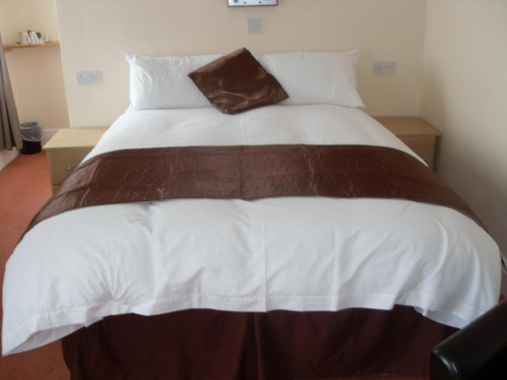 a bed with a white comforter and pillows at Merlewood Hotel in Saundersfoot