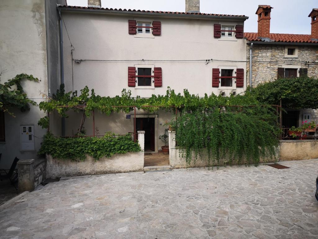 a white house with red shuttered windows and a courtyard at Holiday house Catela in Rakalj