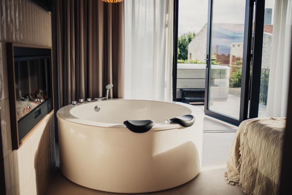 サンティリャーナ・デル・マルにあるNiditas PREMIUM SUITES & SPAの大きな窓のある部屋にある浴槽