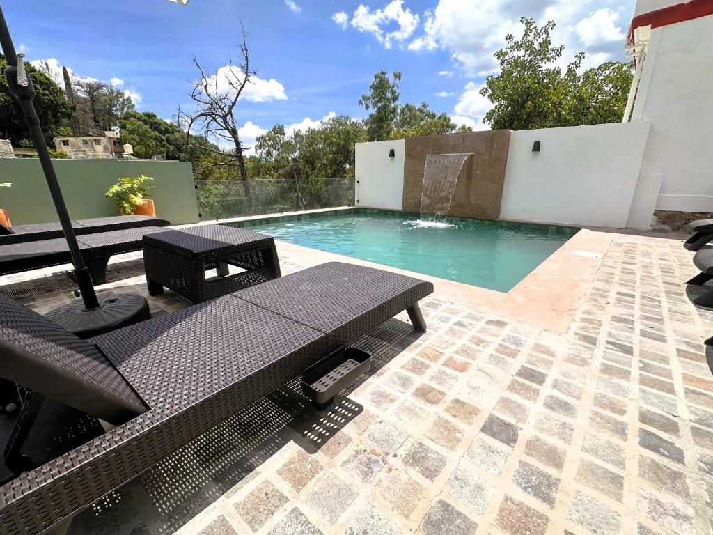 a swimming pool with two benches and a table at Casona San Cayetano Suites & Lofts & Spa by SCE in Guanajuato