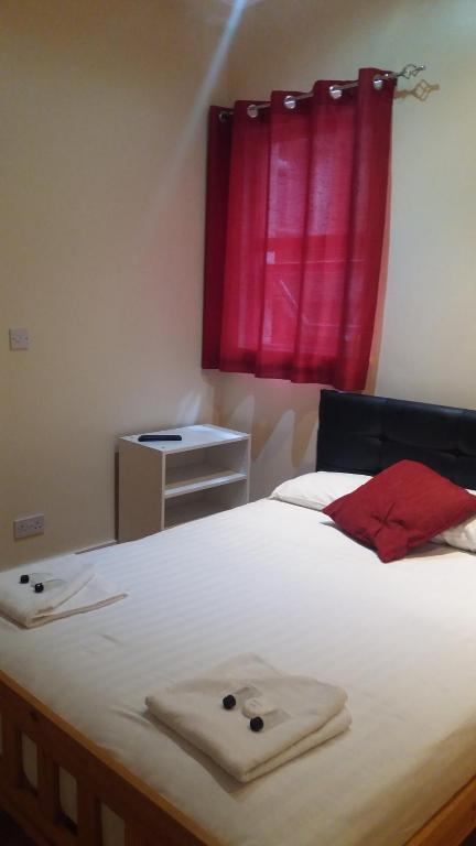 a bedroom with a white bed with a red window at Shepherd's Bush Flats in London