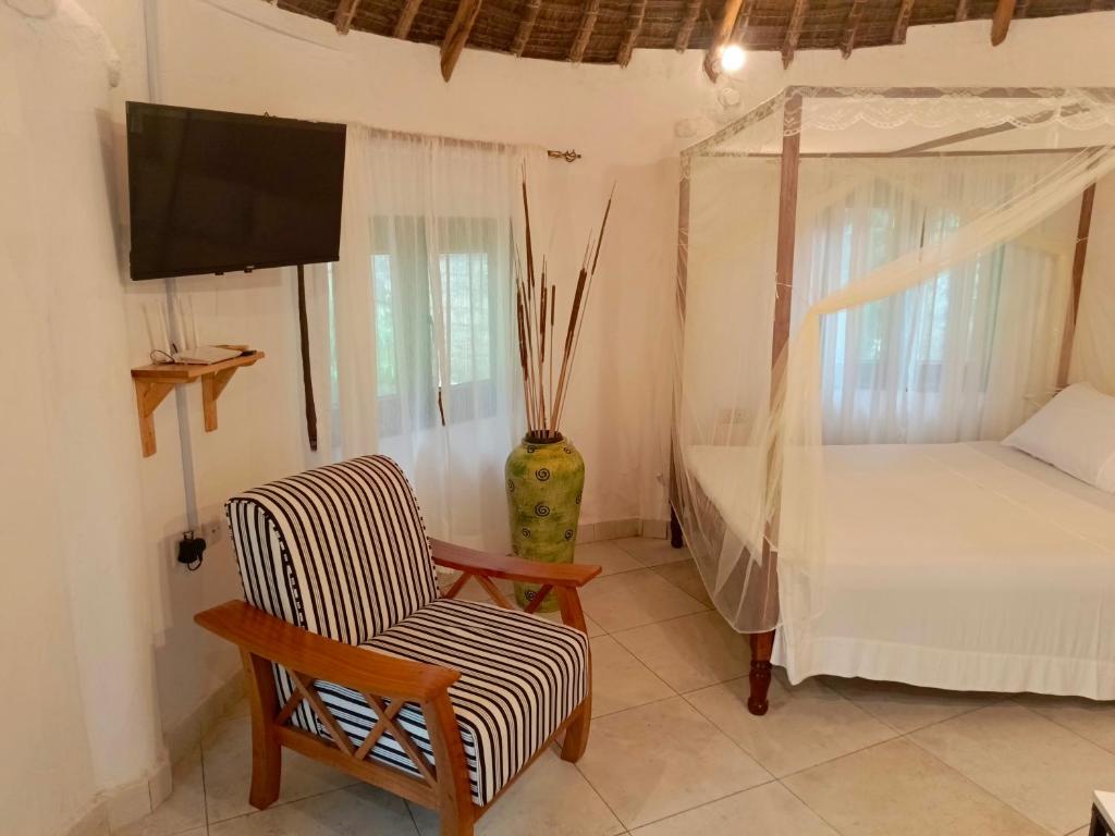 1 dormitorio con 1 cama, 1 silla y TV en The Makuti breeze house, en Mtwapa