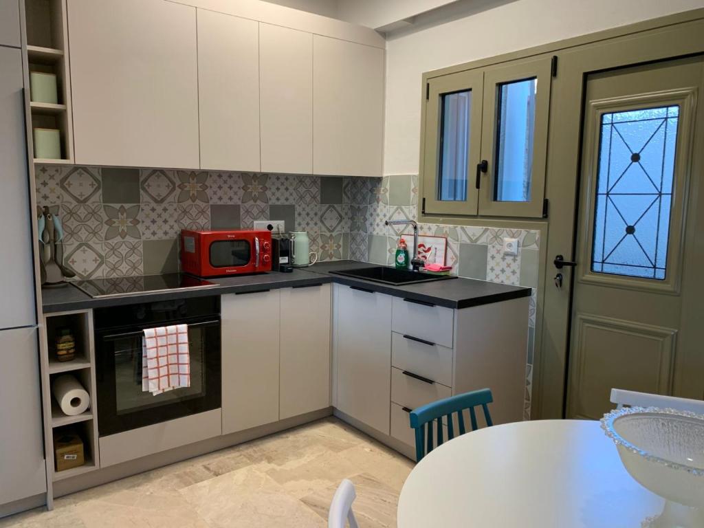 a kitchen with white cabinets and a table and a red microwave at Blue Olive House & Studio in Artemida