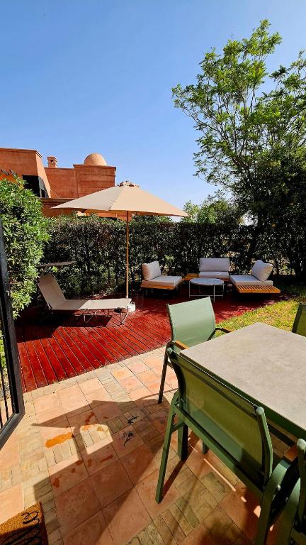 a patio with a table and an umbrella and chairs at Votre Villa Soleil et Chaleureuse in Marrakesh