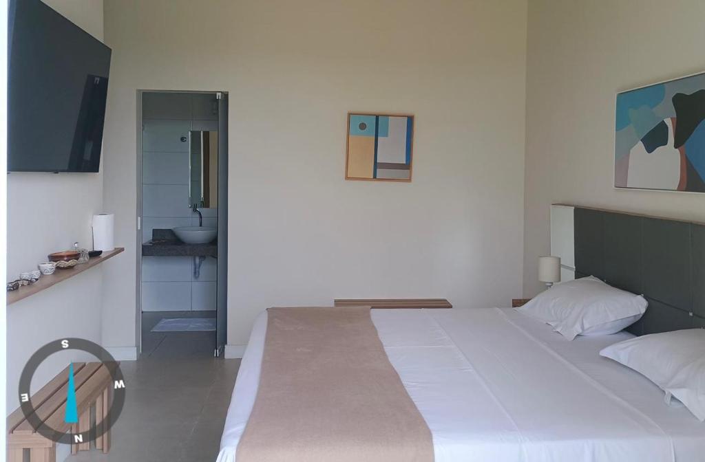 a bedroom with a large white bed and a bathroom at KAA Flat in Belém