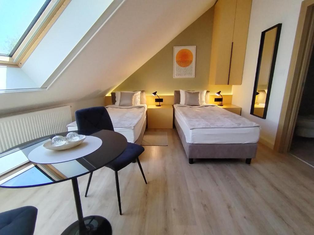 a hotel room with two beds and a table at Vila Karlovčanka smeštaj u centru Sremskih Karlovaca in Sremski Karlovci