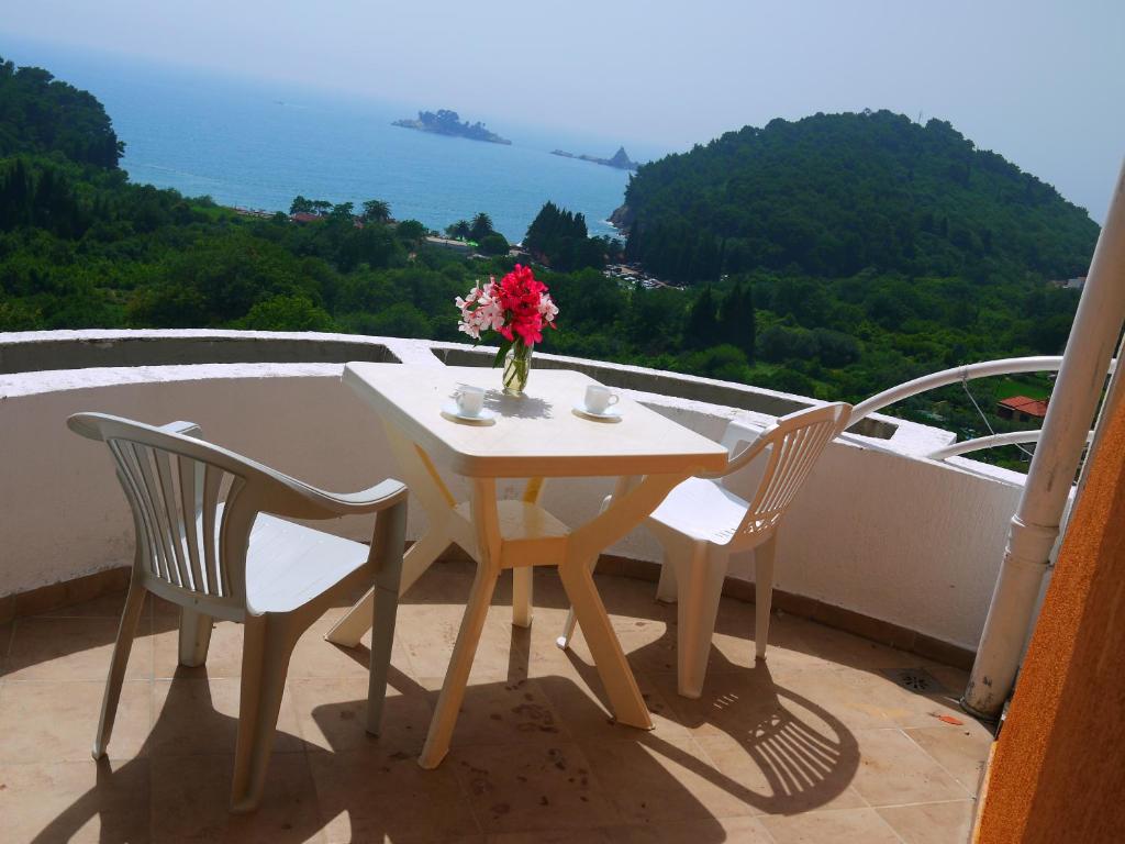 una mesa y 2 sillas y un jarrón de flores en el balcón en Apartments Villa Relax, en Petrovac na Moru
