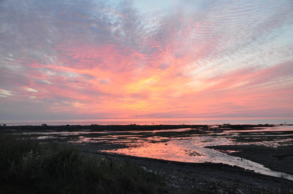 a sunset over a beach with a body of water at Couchers de soleil à Sainte-Flavie in Sainte-Flavie