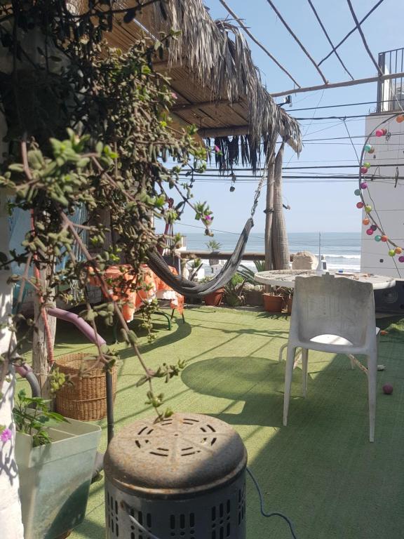 a patio with a hammock and a chair and the ocean at Huanchaco Surf Camp in Huanchaco