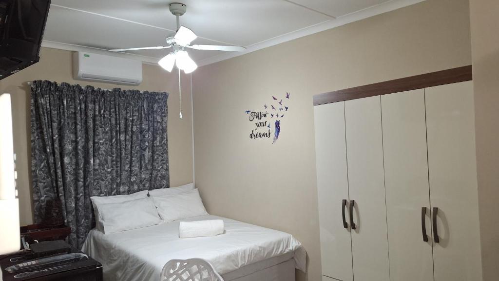 a bedroom with a bed and a ceiling fan at Serenity in Windhoek