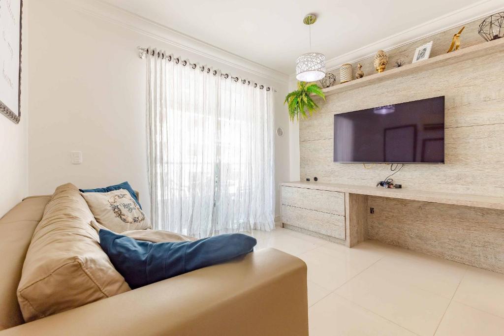 a living room with a couch and a flat screen tv at Apto Confortável e Econômico na Praia de Bombas in Bombas