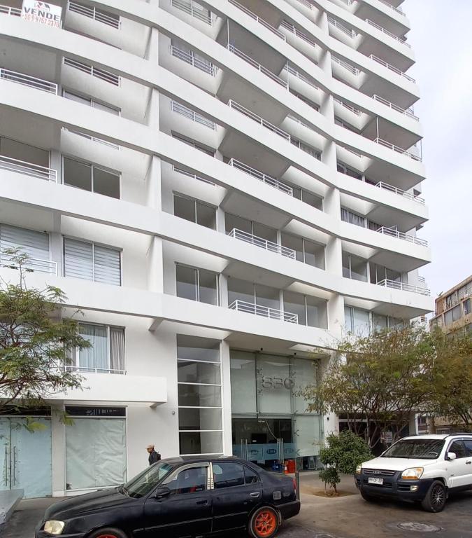 ein schwarzes Auto, das vor einem weißen Gebäude geparkt ist in der Unterkunft Life 01 in Iquique