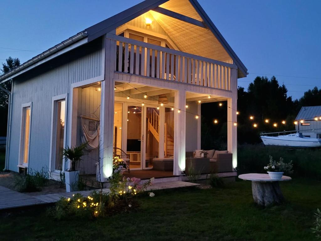 a house with a porch with a deck and a boat at Coco Beach Cupel - Domek AQUA z jakuzzi in Cupel
